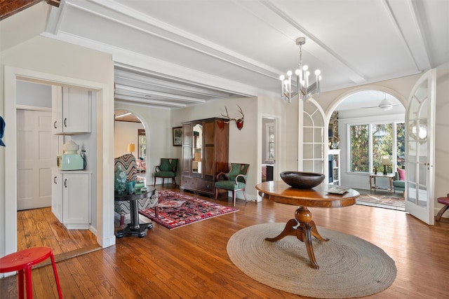 sitting room featuring ceiling fan with notable chandelier, light hardwood / wood-style flooring, beam ceiling, and french doors