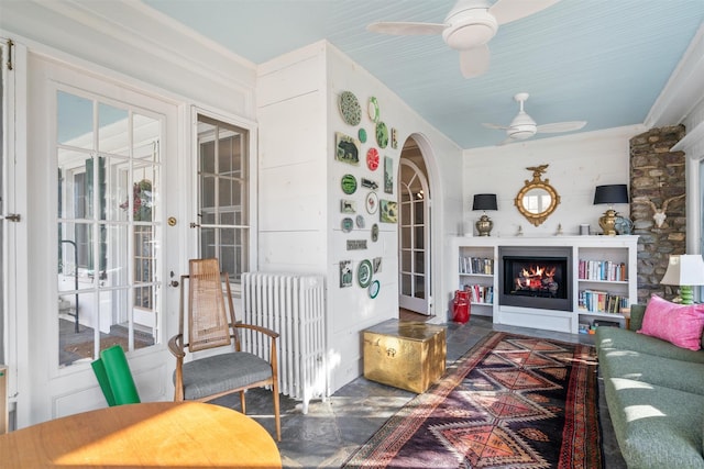 living room with ceiling fan, radiator, french doors, and wooden walls