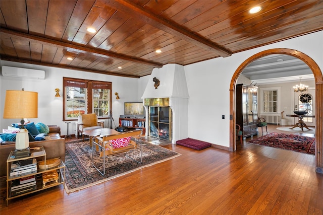 living room featuring a wall unit AC, wood-type flooring, beamed ceiling, radiator, and wooden ceiling