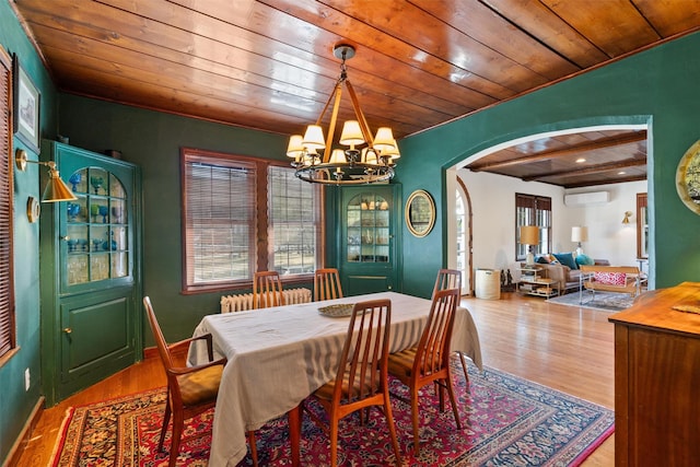 dining space with a wall mounted AC, wood-type flooring, wood ceiling, and an inviting chandelier