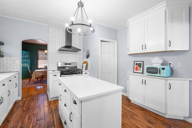 kitchen with decorative backsplash, gas stove, wall chimney exhaust hood, white cabinets, and a center island