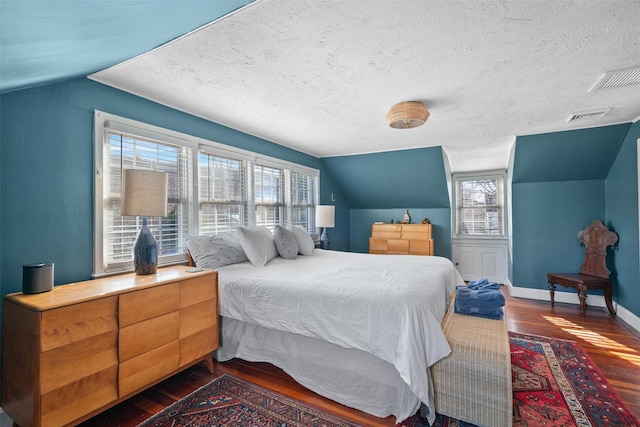 bedroom featuring lofted ceiling, dark wood-type flooring, and a textured ceiling