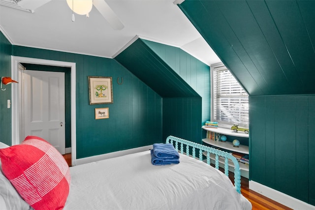 bedroom featuring ceiling fan, hardwood / wood-style floors, wood walls, and lofted ceiling