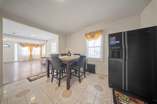 tiled dining room with radiator heating unit and a healthy amount of sunlight