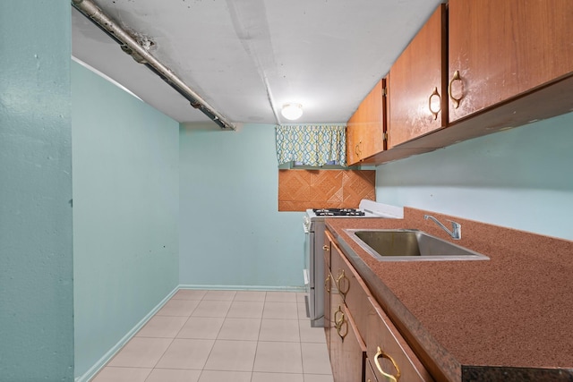 kitchen with sink, light tile patterned floors, decorative backsplash, and white gas range oven