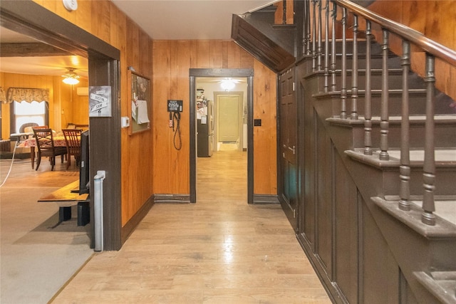 hallway with light wood-type flooring and wood walls