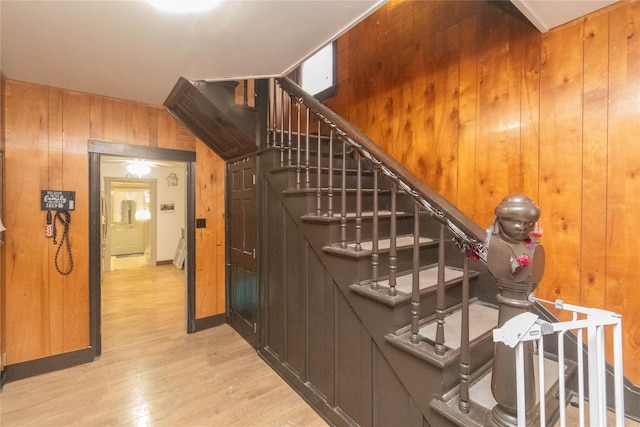 stairs with wood-type flooring and wooden walls