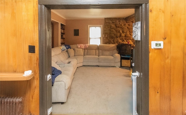 carpeted living room with wood walls and radiator heating unit