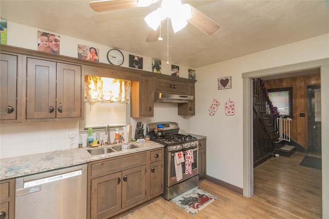 kitchen with tasteful backsplash, sink, stainless steel appliances, and light hardwood / wood-style floors