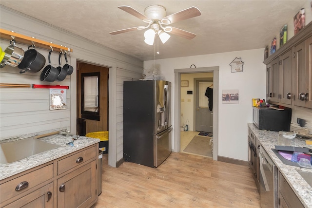 kitchen featuring ceiling fan, sink, light wood-type flooring, light stone countertops, and stainless steel appliances