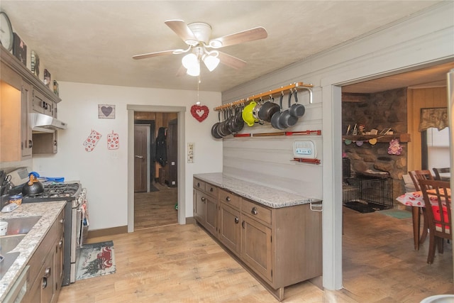 kitchen with ceiling fan, light stone countertops, light hardwood / wood-style flooring, and gas stove