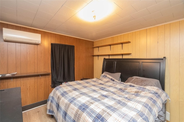 bedroom featuring ornamental molding, a wall unit AC, and light hardwood / wood-style flooring