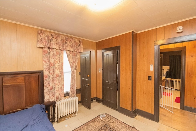 bedroom featuring crown molding, radiator heating unit, and wood walls