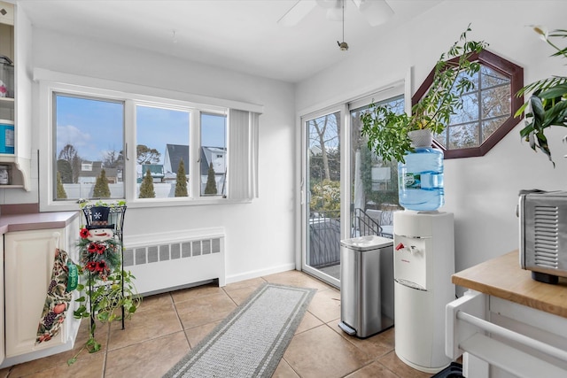 doorway featuring light tile patterned flooring, ceiling fan, and radiator heating unit