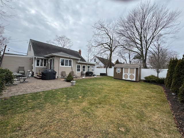 back of house with a storage shed, a yard, and a patio