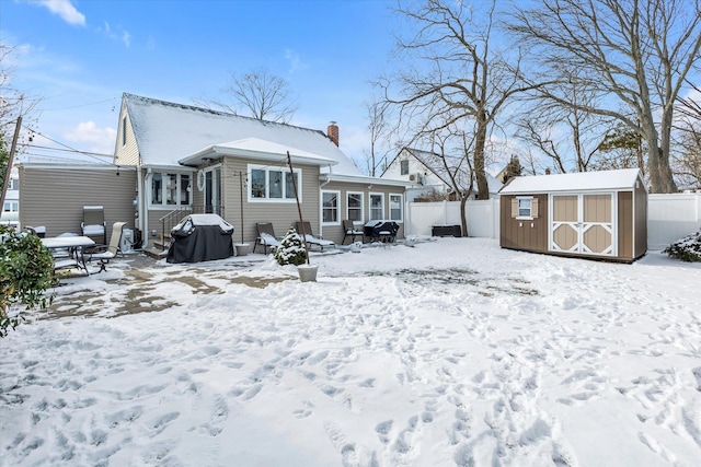 snow covered rear of property with a storage shed