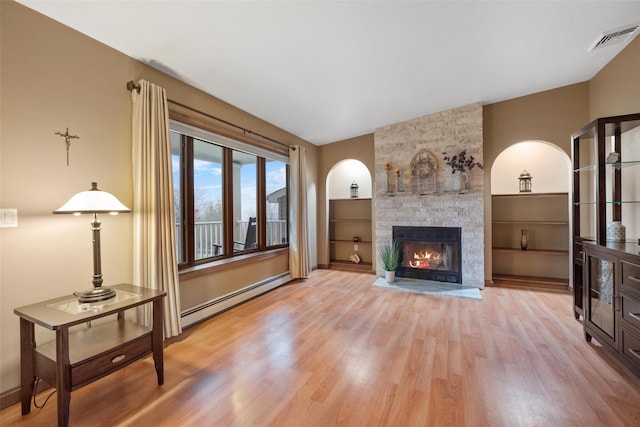 living room featuring light hardwood / wood-style floors, baseboard heating, a fireplace, and lofted ceiling