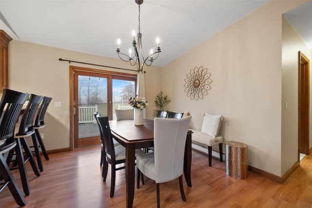 dining area with light wood-type flooring and a notable chandelier