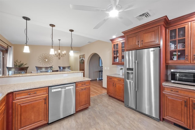 kitchen featuring light wood-type flooring, pendant lighting, light stone countertops, and appliances with stainless steel finishes