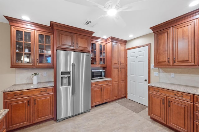 kitchen featuring light stone counters, backsplash, stainless steel appliances, and ceiling fan