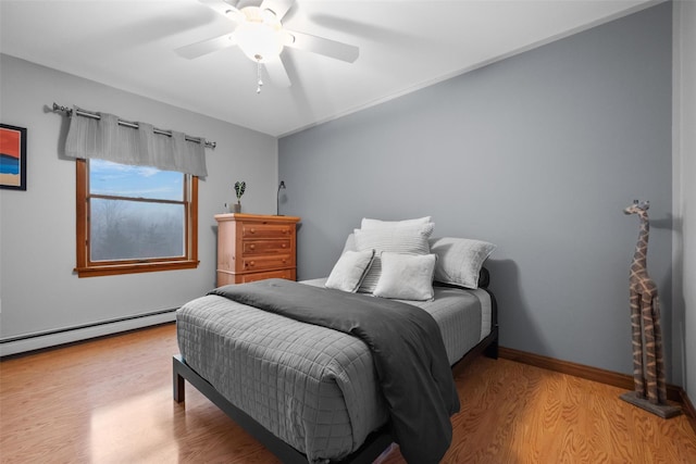 bedroom with ceiling fan, light hardwood / wood-style floors, and a baseboard heating unit