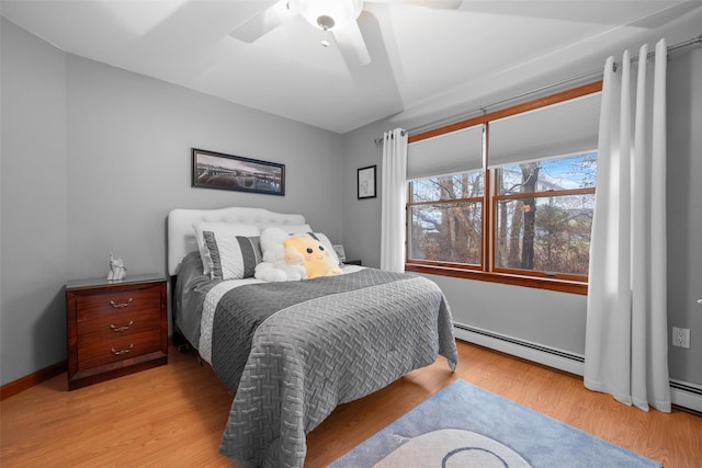 bedroom with ceiling fan, a baseboard heating unit, and light hardwood / wood-style flooring