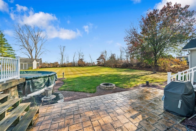 view of patio / terrace with a covered pool, an outdoor fire pit, a storage shed, and a grill