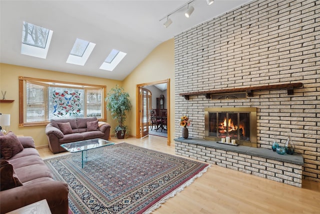 living room with a fireplace, hardwood / wood-style floors, vaulted ceiling, and track lighting