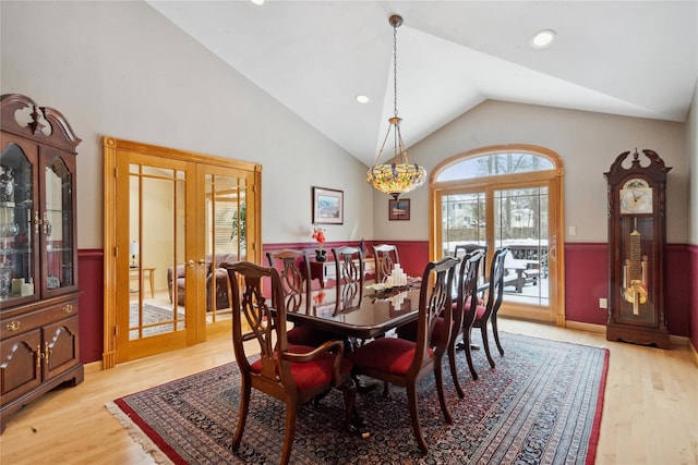 dining room with light wood-type flooring, lofted ceiling, and french doors