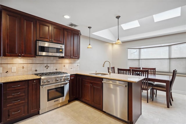 kitchen featuring kitchen peninsula, hanging light fixtures, appliances with stainless steel finishes, sink, and tasteful backsplash