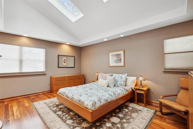 bedroom with light hardwood / wood-style flooring, high vaulted ceiling, and a skylight