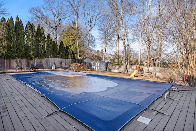 view of pool with a playground and a shed