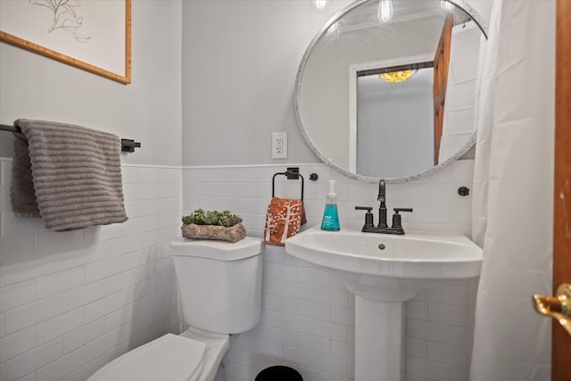 bathroom with toilet and tile walls