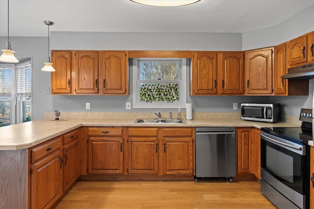 kitchen featuring light hardwood / wood-style floors, kitchen peninsula, stainless steel appliances, decorative light fixtures, and sink