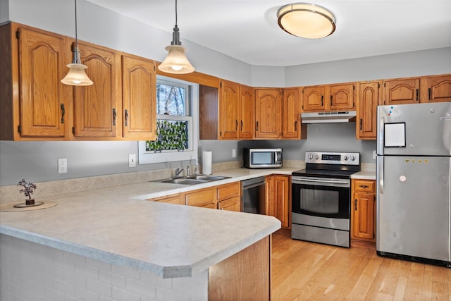 kitchen with light hardwood / wood-style floors, pendant lighting, kitchen peninsula, sink, and stainless steel appliances