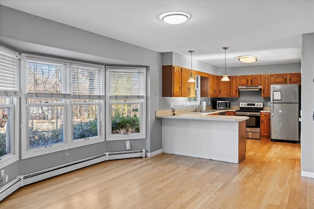 kitchen featuring pendant lighting, kitchen peninsula, sink, stainless steel appliances, and a baseboard radiator