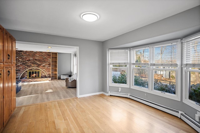 interior space with a baseboard heating unit, a brick fireplace, and light hardwood / wood-style floors