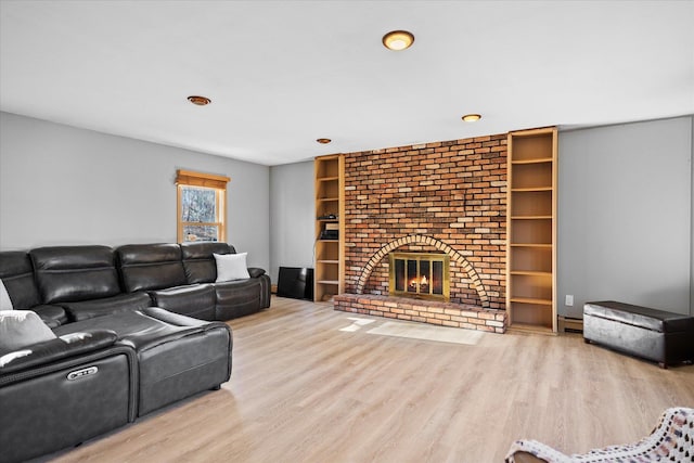 living room featuring a baseboard radiator, wood-type flooring, and a fireplace