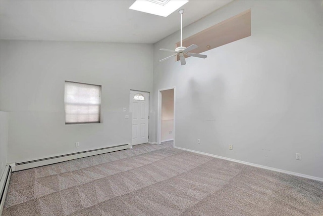 carpeted empty room with a baseboard heating unit, ceiling fan, a skylight, and high vaulted ceiling