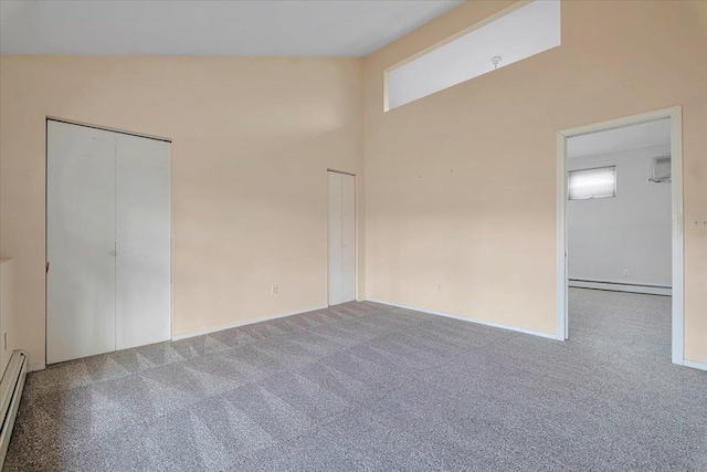 carpeted empty room featuring baseboard heating and lofted ceiling