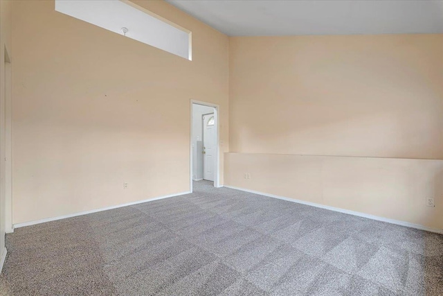 carpeted spare room featuring a towering ceiling