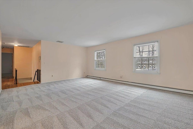 carpeted spare room featuring a baseboard heating unit