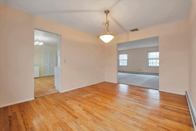 unfurnished room featuring a baseboard radiator, a notable chandelier, and light wood-type flooring