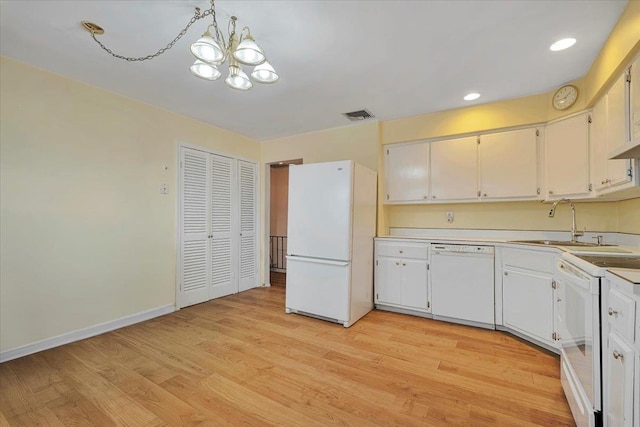 kitchen featuring an inviting chandelier, white appliances, pendant lighting, white cabinets, and sink