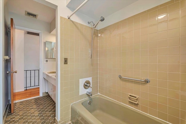 bathroom with tiled shower / bath combo and vanity