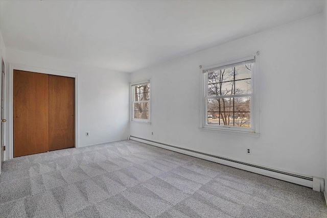 carpeted spare room with a healthy amount of sunlight and a baseboard heating unit