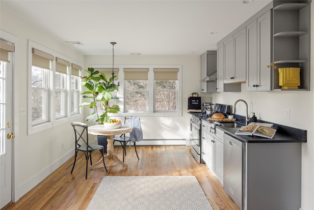 kitchen featuring appliances with stainless steel finishes, gray cabinetry, pendant lighting, wall chimney exhaust hood, and sink