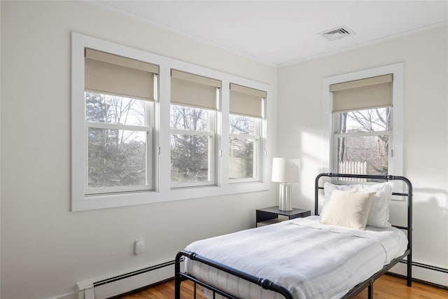 bedroom featuring hardwood / wood-style flooring, crown molding, and a baseboard radiator