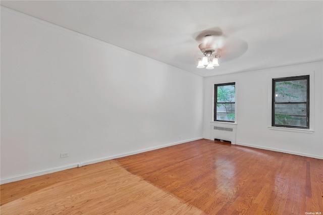 unfurnished room featuring light wood-type flooring, ceiling fan, and radiator heating unit