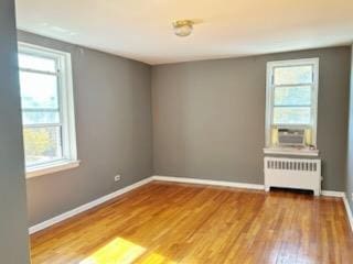 empty room with radiator, cooling unit, and hardwood / wood-style floors